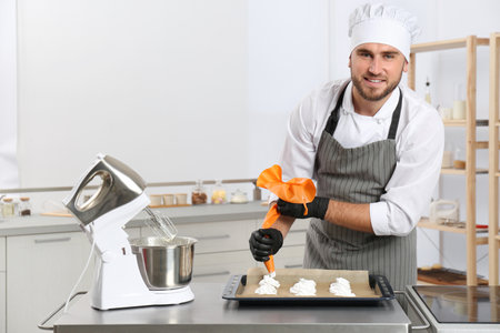 Pastry chef preparing meringues at table in kitchenの写真素材