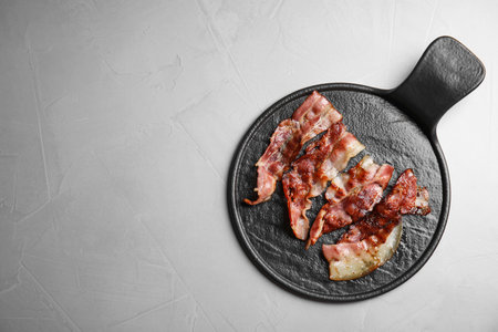 Slices of tasty fried bacon on gray table, top view. Space for textの写真素材