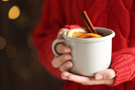 Woman holding cup of tasty mulled wine on blurred backgroundの写真素材