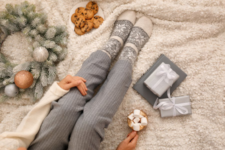 Young woman with cocoa and cookies sitting on light blanket, top view. christmas holidayの写真素材