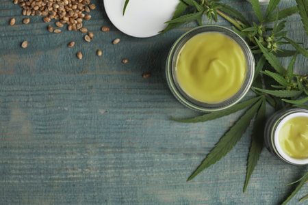 Jars of hemp cream and seeds on blue wooden table, flat lay with space for text. organic cosmeticsの写真素材