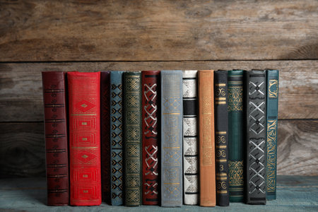 Stack of hardcover books on light blue table against wooden backgroundの写真素材