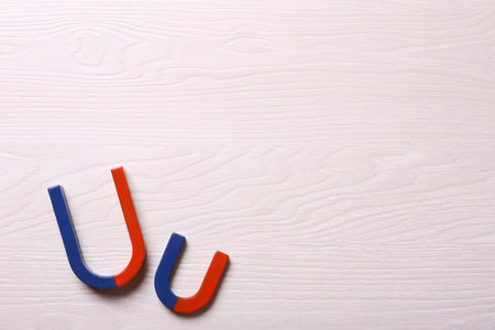 Red and blue horseshoe magnets on light wooden background, flat lay. Space for textの写真素材
