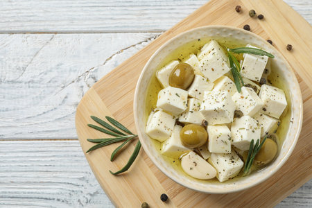 Flat lay composition with pickled feta cheese in bowl on white wooden tableの写真素材
