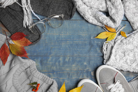 Flat lay composition with autumn clothes on blue wooden background, space for textの写真素材