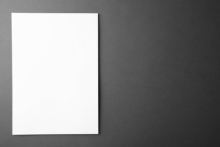 Blank paper sheet on dark gray background, top view. Mock up designの写真素材