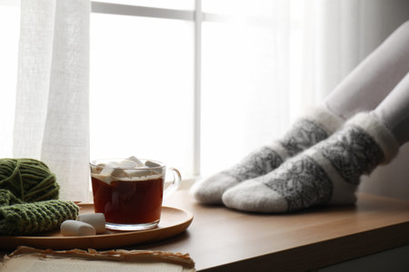Woman and cup of hot winter drink near window indoors, closeupの写真素材