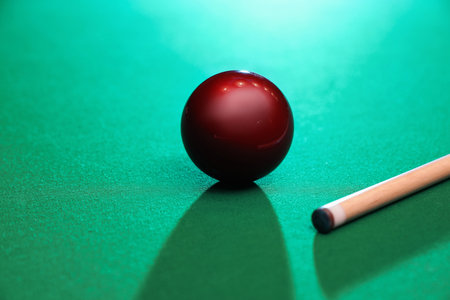 Red billiard ball and cue on tableの写真素材