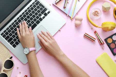 Young beauty blogger working with laptop and accessories on light pink background, top viewの写真素材