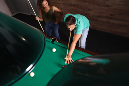 Young man and woman playing billiard indoors, above viewの写真素材