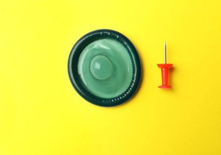 Blue condom and pin on yellow background, flat layの写真素材