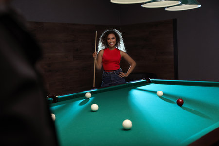 Young African-American woman with cue near billiard table indoorsの写真素材