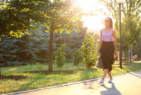 Beautiful young woman in park on sunny dayの写真素材