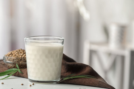 Glass of hemp milk on white table against blurred backgroundの写真素材