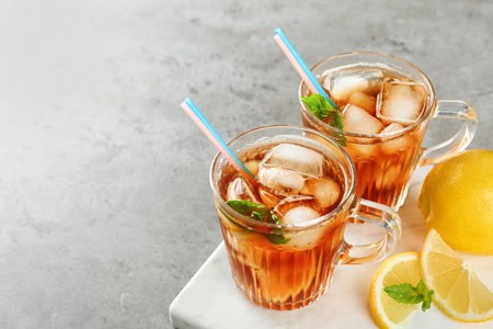 Cups of refreshing iced tea on light table. Space for textの写真素材