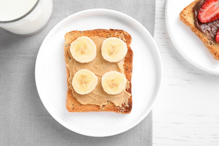 Flat lay composition of toast with peanut butter on white wooden table. healthy breakfastの写真素材
