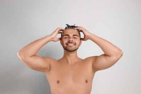 young man washing hair on white backgroundの写真素材