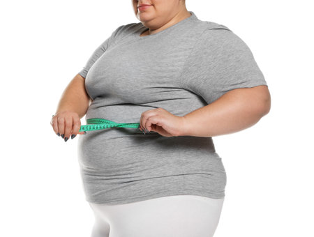 Overweight woman measuring waist with tape on white background, closeupの写真素材