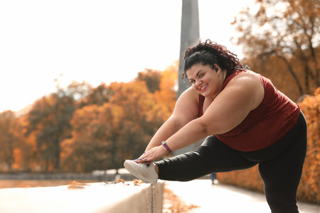 Beautiful overweight woman doing sport exercises in parkの写真素材