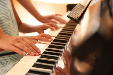Young woman teaching little girl to play piano indoors, closeupの写真素材