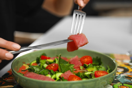 Young woman eating tasty salad with red fish at table, closeupの写真素材