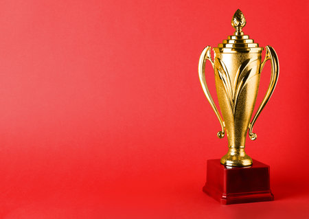 Golden trophy cup on red background. Space for textの写真素材