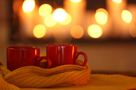 Cups of hot drink on knitted scarf against blurred background. winter atmosphereの写真素材