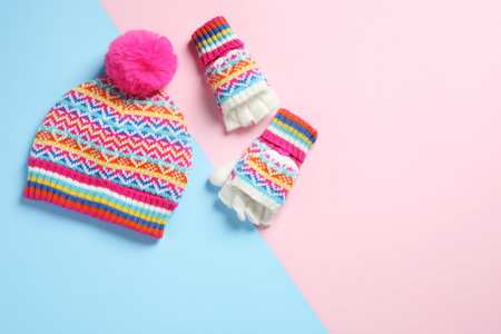 Warm knitted hat and mittens on color background, flat lay. Space for textの写真素材