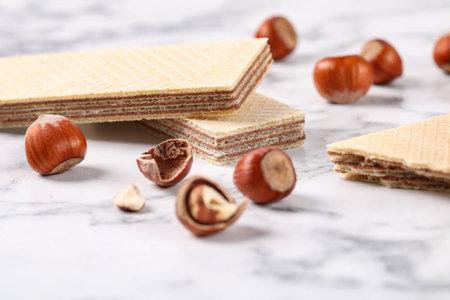 Delicious wafers with hazelnuts on marble background, closeupの写真素材