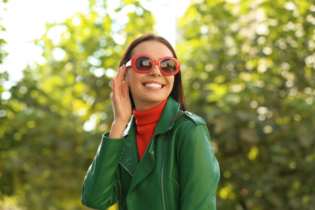 Beautiful woman wearing red sunglasses in green parkの写真素材