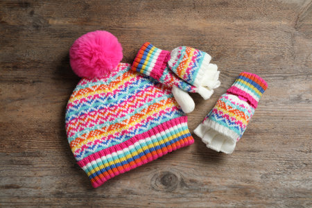 Warm knitted hat and mittens on wooden background, flat layの写真素材