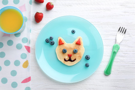 Tasty pancake served with berries and juice on white wooden table, flat lay. creative idea for kids breakfastの写真素材