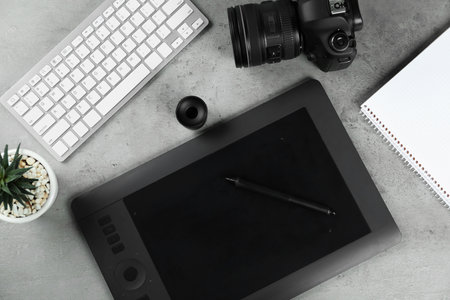 Flat lay composition with graphic tablet and camera on gray stone table, space for text. Designer's workplaceの写真素材