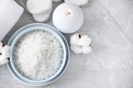 White sea salt and supplies for spa scrubbing procedure on gray marble table, flat layの写真素材