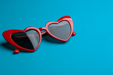 Stylish heart shaped sunglasses on blue background. fashion accessory