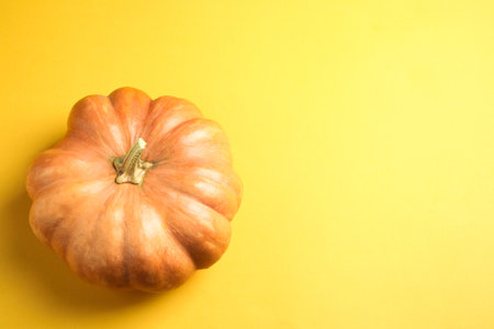 Fresh ripe pumpkin on yellow background, top view with space for text. holiday decorationの写真素材