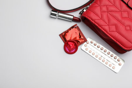 Flat lay composition with birth control pills and condoms on light background, space for text. safe sex conceptの写真素材