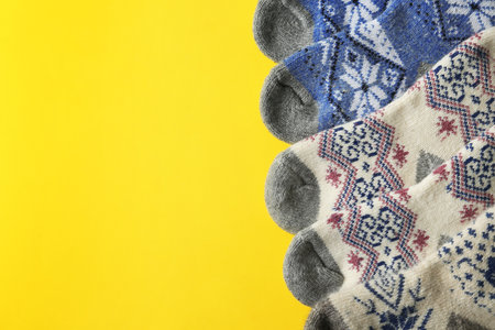Soft knitted socks on yellow background, flat lay with space for text. winter clothesの写真素材