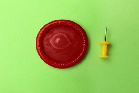 Red condom and pin on green background, flat layの写真素材