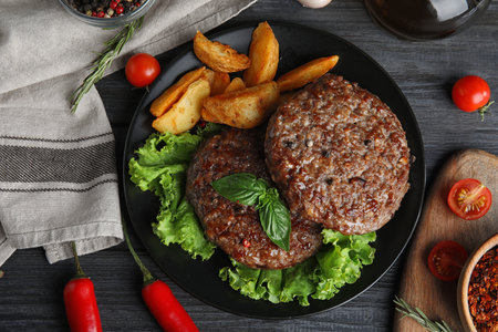 Flat lay composition with grilled meat cutlets for burger on black wooden tableの写真素材