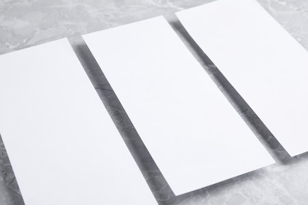 Blank palm cards on light gray marble background, closeup. Mock up design