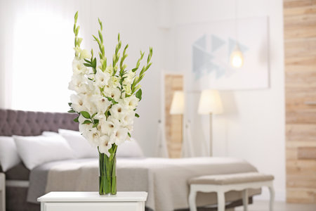 Vase with beautiful white gladiolus flowers on wooden table in the bedroom. Space for textの写真素材