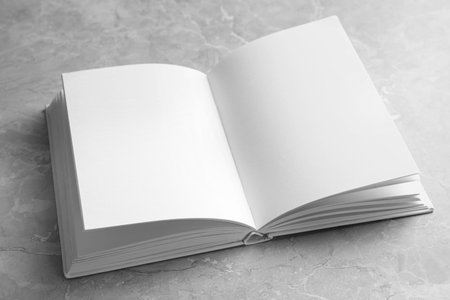 Open book with blank pages on light gray marble background. Mock up design