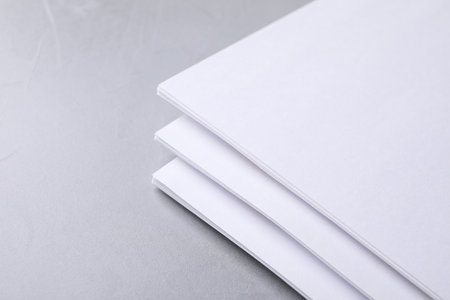 Blank paper sheets on light gray stone background, closeup. Mock up designの写真素材