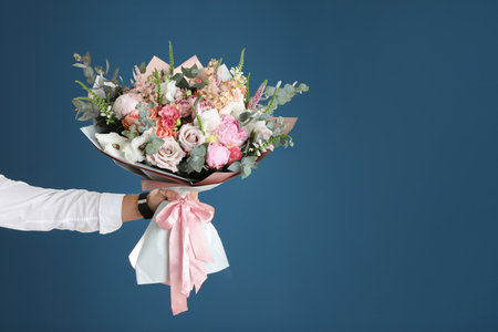 Man holding beautiful flower bouquet on blue background, closeup view. Space for textの写真素材