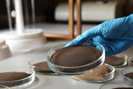 Woman holding Petri dish with soil sample over table, closeup. laboratory researchの写真素材
