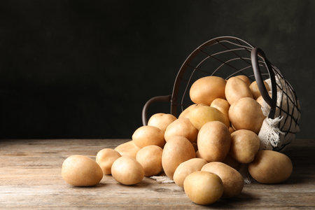 Raw fresh organic potatoes on wooden table against dark background. Space for textの写真素材