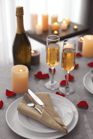 Romantic table setting with burning candles and rose petals indoorsの写真素材