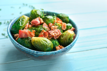 Tasty roasted Brussels sprouts with bacon on light blue wooden table, closeupの写真素材