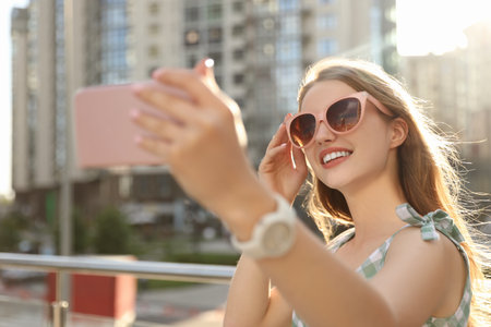 Beautiful young woman with sunglasses taking selfie outdoorsの写真素材